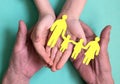 the hands of a man and a child hold a silhouette of a family with children cut out of yellow paper. Royalty Free Stock Photo