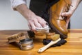 Hands of man cleaning premium derby boots with variety of brushes