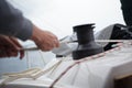 Hands of a man coiling up a rope, the sheet on a winch on a sailboat