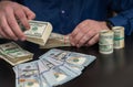 Hands of a man counting wads of dollar banknotes