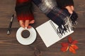 Hands of man with a cup of coffee and scarf at wooden table with notebook and pen and autumn leaves Royalty Free Stock Photo