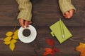 Hands of man with a cup of coffee at a wooden table with notebook and pen and autumn leaves Royalty Free Stock Photo