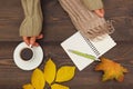 Hands of man with a cup of espresso and scarf at wooden table with notebook and pen and autumn leaves Royalty Free Stock Photo