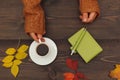 Hands of man with a cup of espresso at a wooden table with notebook and pen and autumn leaves Royalty Free Stock Photo