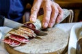 Hands of a man cutting fuet with a knife on wood. fuet, espetec, tastet, petador or secallona is a typical sausage of the Catalan Royalty Free Stock Photo