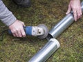 hands of man cutting the stove pipe, working with portable grinder machine on the grass Royalty Free Stock Photo