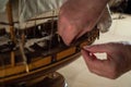 A hands of a man delicately working a model of a miniature ship piece by piece Royalty Free Stock Photo