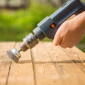 Hands man with electrical rotating brush metal disk sanding a piece of wood