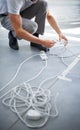 Hands, man and electrician plug connection, power and electricity in office. Cord, wire and cable on floor, socket and Royalty Free Stock Photo