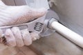 Hands of a man in gloves are installing the heater system in the house and checking pipes by the wrench Royalty Free Stock Photo