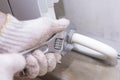 Hands of a man in gloves are installing the heater system in the house and checking pipes by the wrench Royalty Free Stock Photo