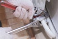 Hands of a man in gloves are installing the heater system in the house and checking pipes by the wrench Royalty Free Stock Photo