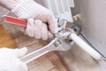 Hands of a man in gloves are installing the heater system in the house and checking pipes by the wrench Royalty Free Stock Photo