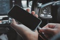 Hands man holding and charging battery mobile smartphone in car with cable in luxury interior car design. The phone is charging Royalty Free Stock Photo