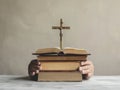 Hands of a man holding a cross on a stack of old books Generative AI Royalty Free Stock Photo