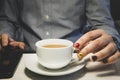 Hands of man holding cup of tea and uses a smartphone on the wood table. man with painted nails. Design of male nails. men Royalty Free Stock Photo