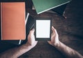 Hands of man holding ebook reader between stacks of books Royalty Free Stock Photo