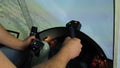 Hands of man holding steering wheel in aircraft simulator, maneuvering flight