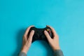 Hands of a man holding a video game console controller on a blue background Royalty Free Stock Photo