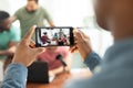 Hands of man with mobile phone filming multiracial male coworkers recording podcast in office