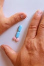 Hands of a man next to pills that symbolize a penis with an erection. Metaphor of male virility. Medicine related to male