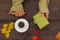 Hands of man with a pen and notebook at a wooden table with cup of coffee and autumn leaves Royalty Free Stock Photo