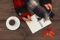 Hands of man with a pen and notebook at a wooden table with cup of coffee and autumn leaves and scarf Royalty Free Stock Photo