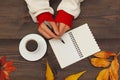 Hands of man with a pen and notebook at a wooden table with cup of espresso and autumn leaves Royalty Free Stock Photo