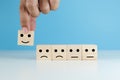 hands of man pick up selection wooden cube blocks with smile emotion icons and not selected unhappy emotion blue background.