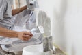 Hands man plasterer construction worker at work closeup, takes plaster from bucket and puts it on trowel to plaster the wall,