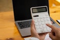 Hands of a man pressing a calculator and making money at the home office by writing a report on his laptop. business man`s hand ca Royalty Free Stock Photo