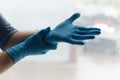 Hands of man putting on blue latex rubber gloves
