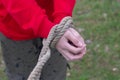 The hands of a man in a red jacket tied with a thick rope outdoors Royalty Free Stock Photo