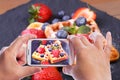 Hands of man with smartphone taking photo Homemade traditional Belgian waffles with fresh fruits, berries and powdered