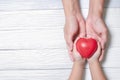 Hands of man and son holding red heart on wooden background Royalty Free Stock Photo