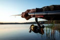 Hands of a man in a Urp plan hold a fishing rod, a fisherman catches fish at dawn. Fishing hobby vacation concept. Copy space Royalty Free Stock Photo