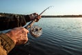 Hands of a man in a Urp plan hold a fishing rod, a fisherman catches fish at dawn. Fishing hobby vacation concept. Copy space Royalty Free Stock Photo