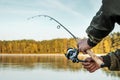 Hands of a man in a Urp plan hold a fishing rod, a fisherman catches fish at dawn. Fishing hobby vacation concept. Copy space Royalty Free Stock Photo