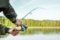 Hands of a man in a Urp plan hold a fishing rod, a fisherman catches fish at dawn. Fishing hobby vacation concept. Copy space Royalty Free Stock Photo