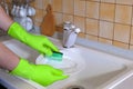 Hands of a man washing dishes in the kitchen with rubber gloves. The concept of clean dishes Royalty Free Stock Photo