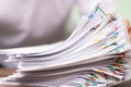 Hands of a man in a white shirt searching for contract agreement documents in Stack of Group report papers clipped in color clips