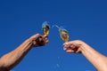 Hands of man and woman clink wineglasses of sparkling white wine