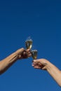 Hands of man and woman clink wineglasses of sparkling white wine