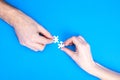 Hands of man and woman collect puzzles on a blue background background. Conceptual image of joint cooperation in the family. View