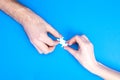Hands of man and woman collect puzzles on a blue background background. Conceptual image of joint cooperation in the family. View