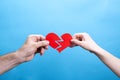 Hands of man and woman tearing a red paper heart on a blue background Royalty Free Stock Photo