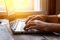 Hands of a man working at a computer laptop by the window in the sunlight Royalty Free Stock Photo