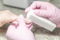 Hands during a manicure session, filing nails with grinding blocks at the master in the salon