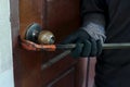 Hands of Masked thief with balaclava using crowbar to breaking into a house at night time. Crime concept. Royalty Free Stock Photo