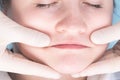 Hands of a massage therapist working on the neck and face area, top view, close-up Royalty Free Stock Photo